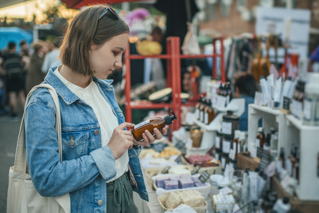 Shopper exploring label on organic body care goods at an open-air market with zero waste concept