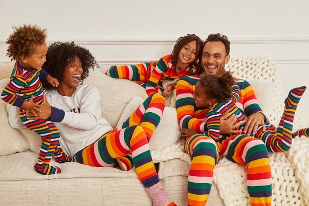 Happy family in striped pajamas by Gap playing around on a couch.