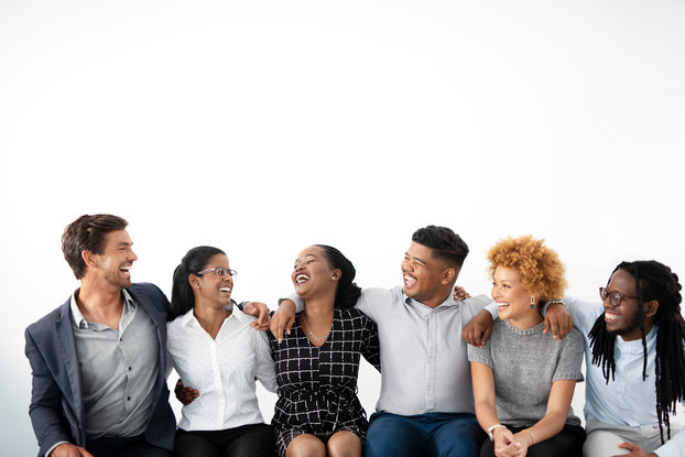 Group of happy co-workers sitting on a bench with their arms around each other.