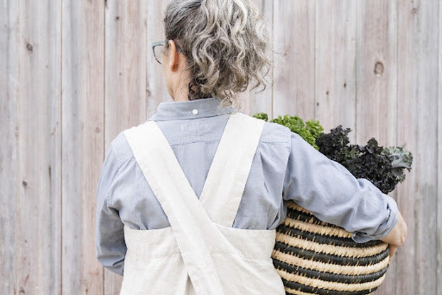 Heidi Barr, founder of Kitchen Garden Textiles, with her back to the camera holding a potted plant.