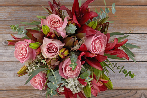 top view of red and pink floral bouquet on wood background