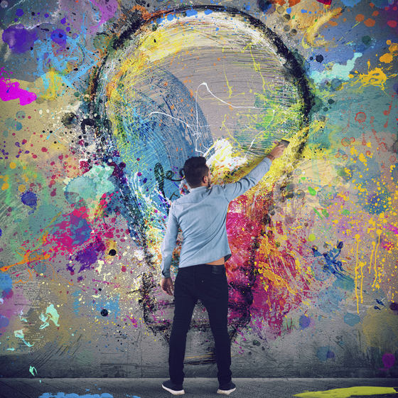 man painting a lightbulb on a wall
