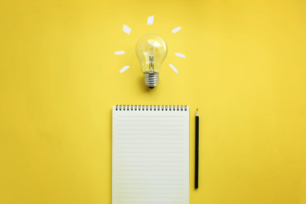 lightbulb and notebook on yellow background