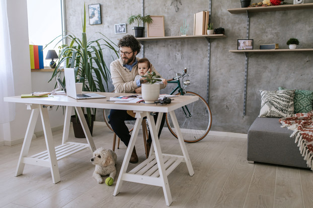 man working remotely with baby and dog