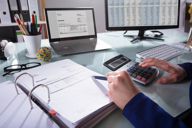 person doing finances with calculator and computer