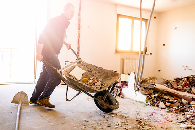 man with wheelbarrow in damaged building