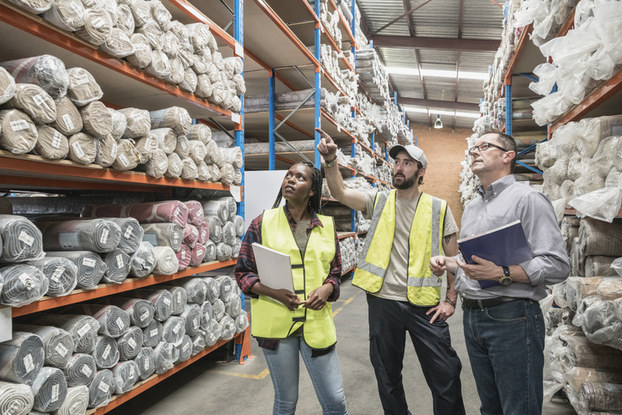 three people in a factory looking at goods on shelves