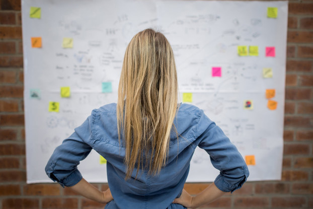 woman looking at whiteboard with notes