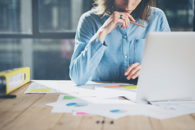 woman sitting at desk with paperwork and laptop