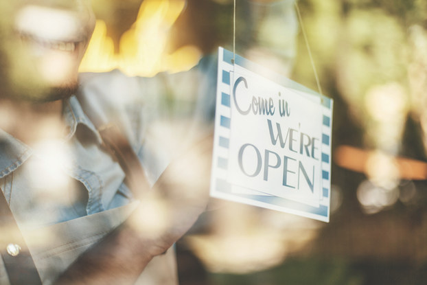 man putting business open sign on front door