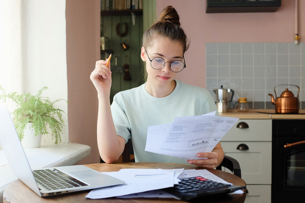 woman sitting at table with laptop and papers