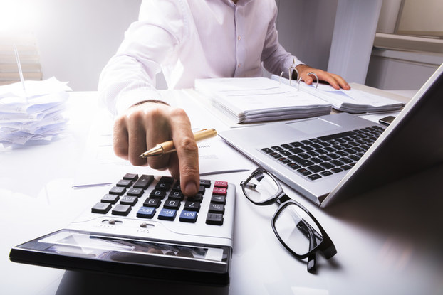 person sitting at desk with laptop and calculator