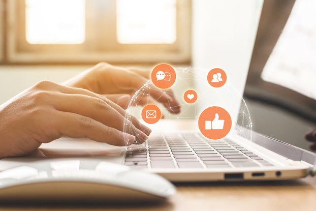 person on laptop with images of social media icons floating