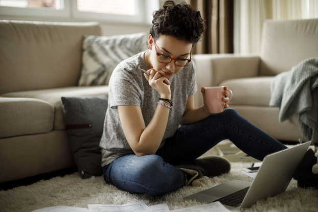 woman sitting on floor in home with laptop and coffee