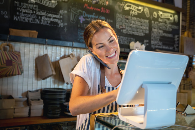 woman on phone and computer in restaurant