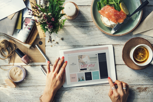 woman using tablet on table with food and coffee