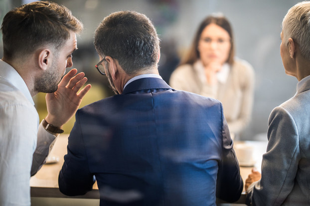 professionals in a meeting whispering