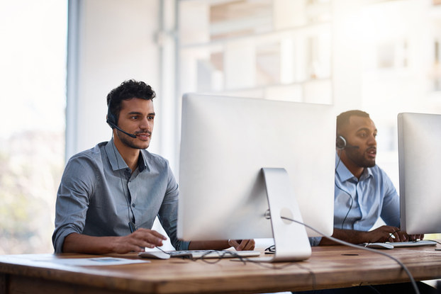 two male coworkers working next to each other on computers