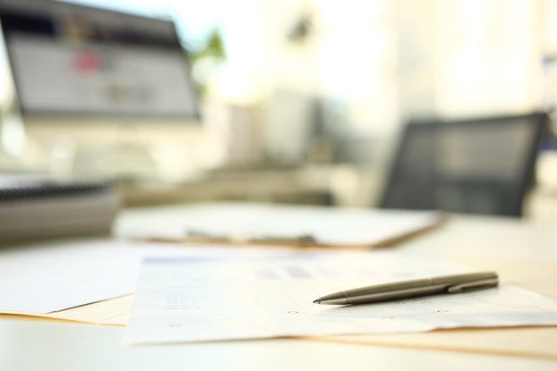 papers on desk with pen and computer