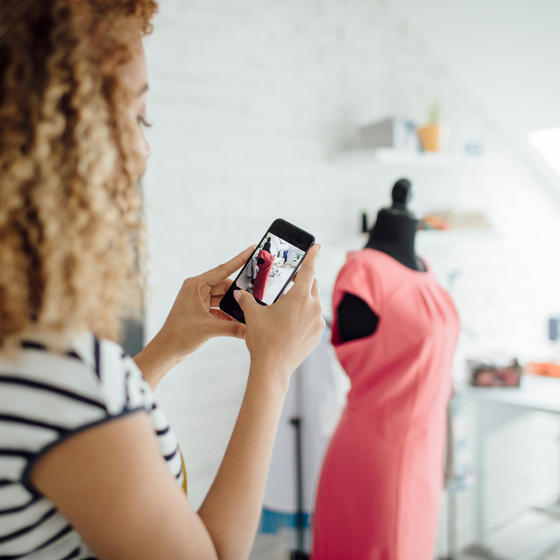 woman seamstress taking photo of dress on a mannequin