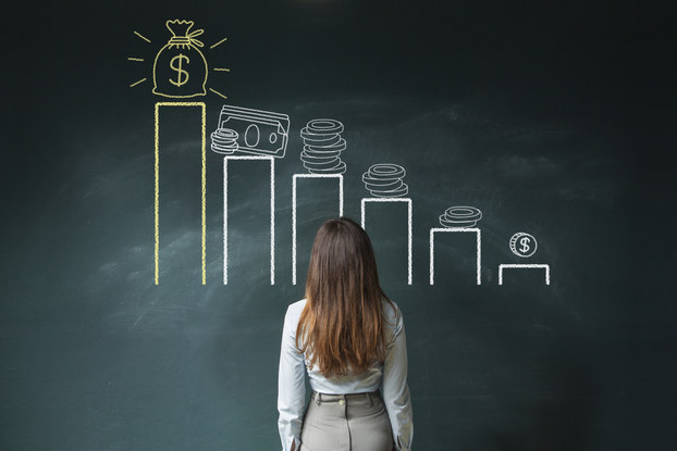 woman staring at pictures of money on chalkboard