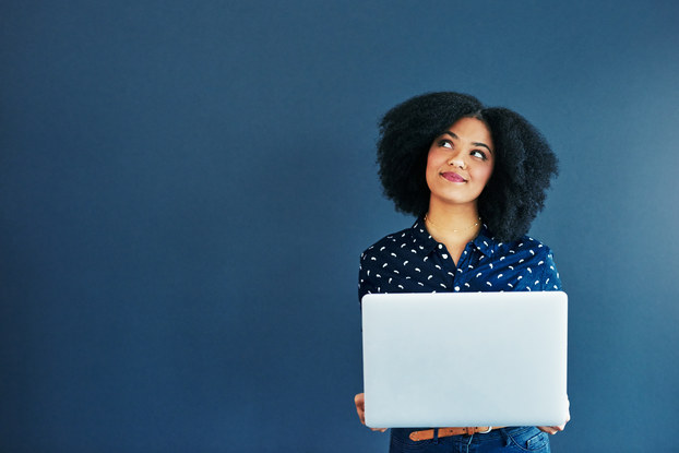 woman smiling and thinking while holding a laptop
