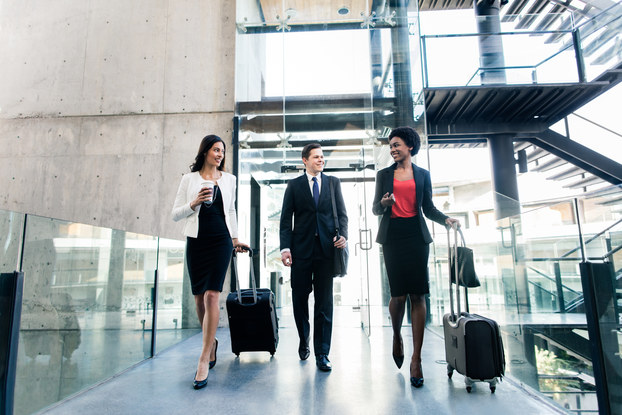 three coworkers walking with suitcases