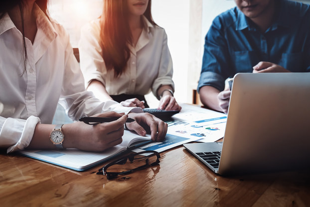 three coworkers in a meeting with laptop and paperwork