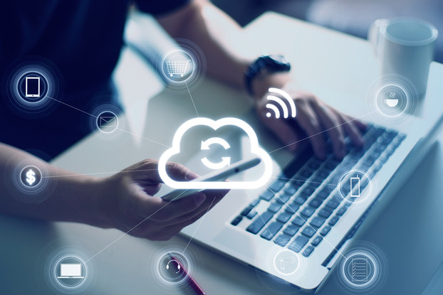 person on laptop and phone with cloud storage icons