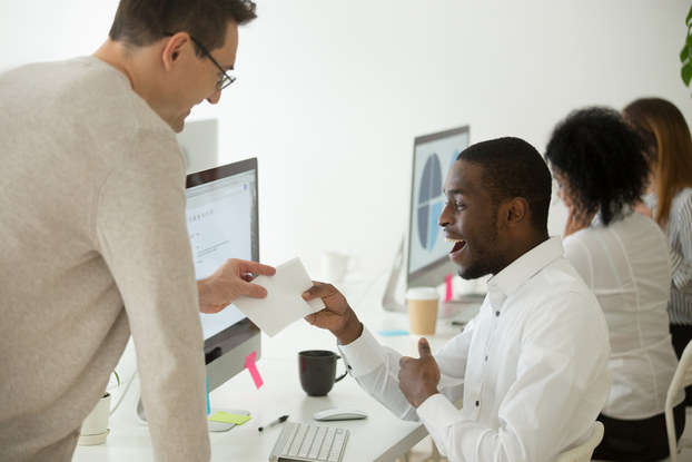 boss giving check to employee at work