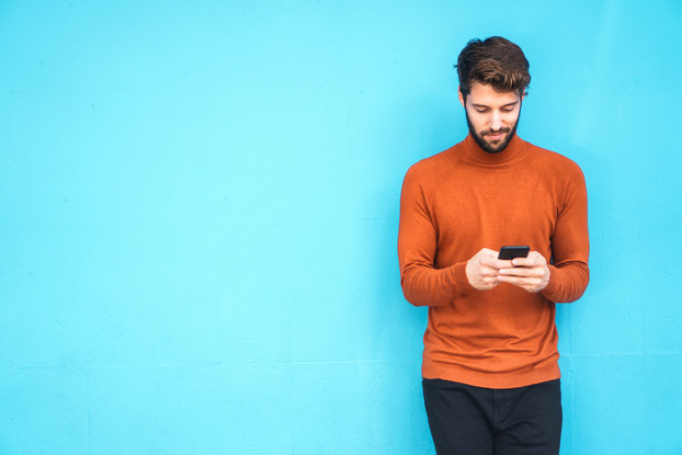 man standing looking down at phone