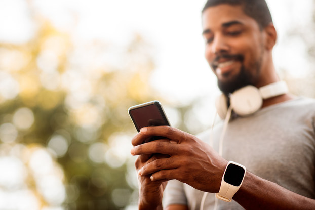 man wearing headphones looking at smartphone