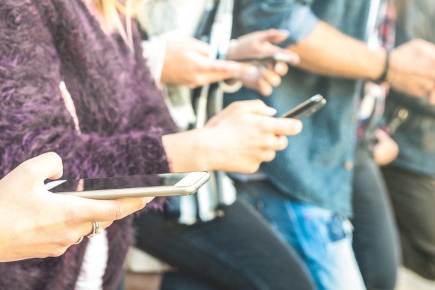 people standing in a row on their phones