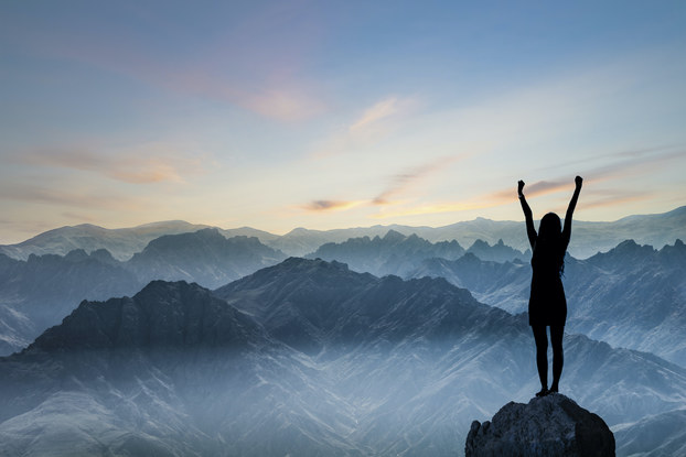 woman standing on top of a mountain with her arms up