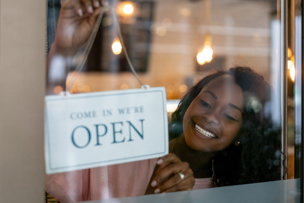 woman holding open sign in business window