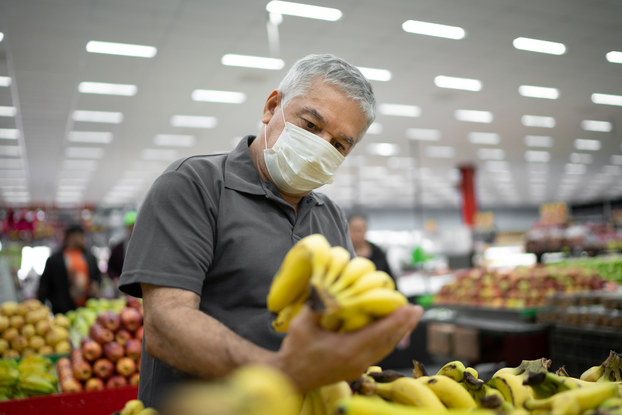 man in supermarket looking at bananas