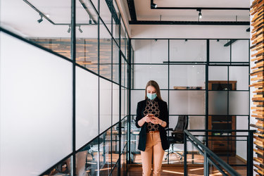  Woman uses phone in office after COVID-19 pandemic. 