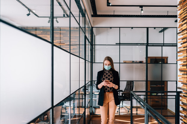 Woman uses phone in office after COVID-19 pandemic.