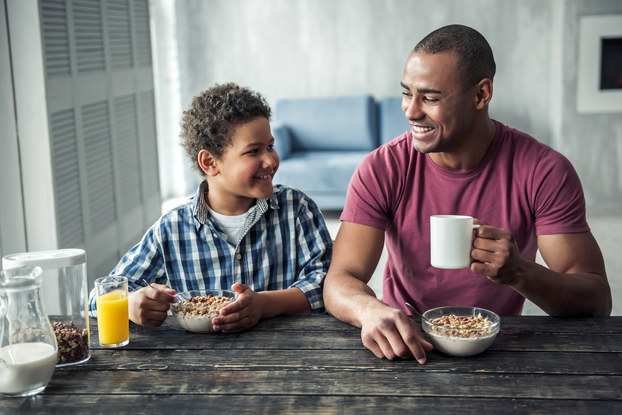 father and son at breakfast table eating cereal
