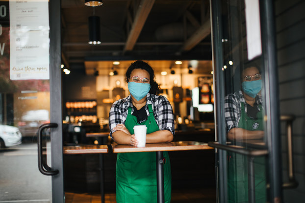 starbucks employee in a mask holding a beverage