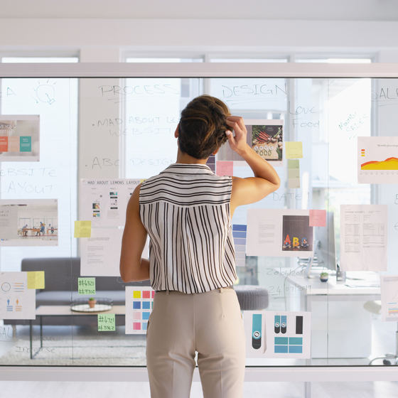 woman writing on clear board in office