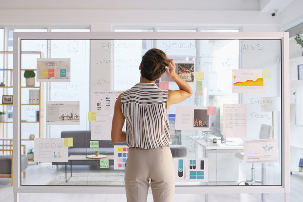 woman writing on clear board in office