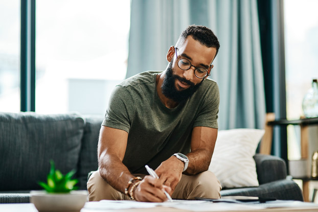 man writing on pad in living room