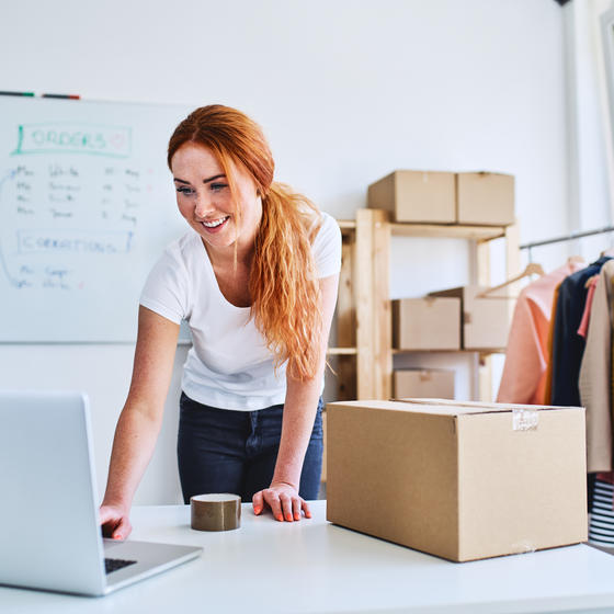 woman on laptop boxing up products