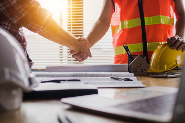 Construction worker shaking hands at desk