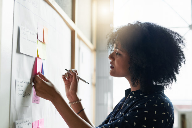 woman working and writing notes on whiteboard