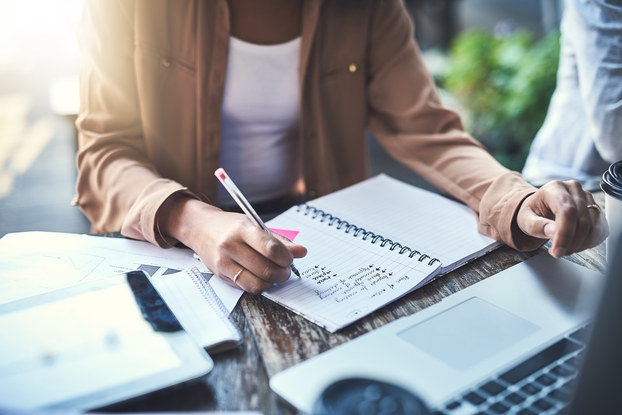 A business owner plots out a business plan in a notebook and on a laptop.