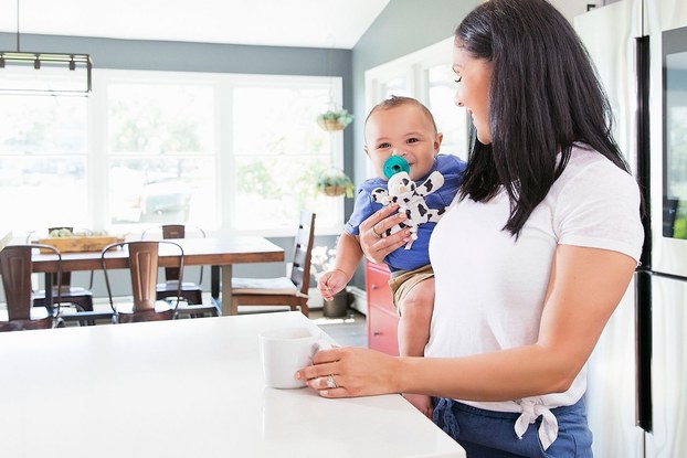 mom holding baby in kitchen with wubbanub pacifier