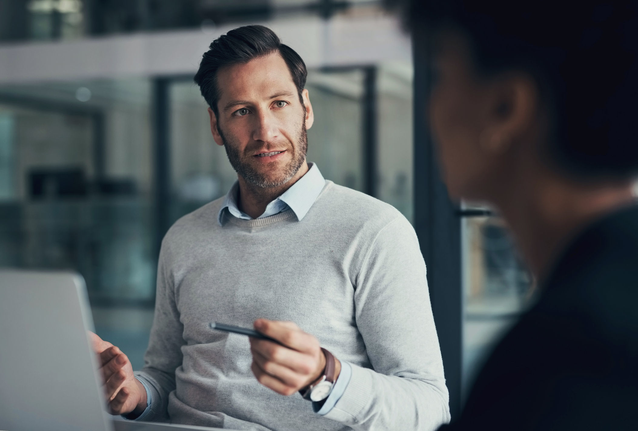 Two men are engaged in a discussion. One man faces the camera and is looking at the other individual while gesturing to make his point.