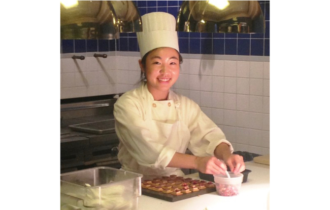 A woman in a chef's outfit working in a kitchen.